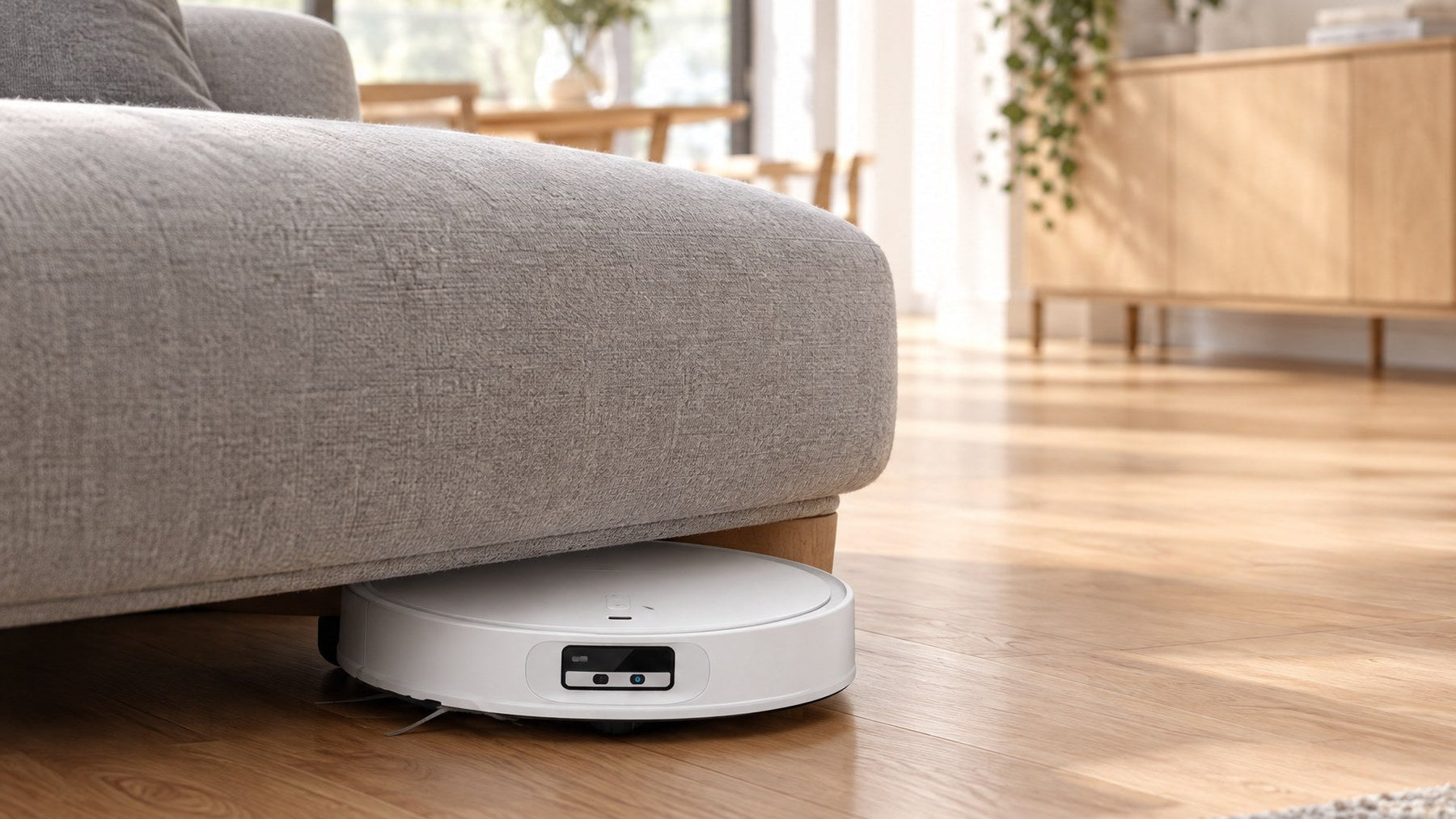 Slim Roborock Qrevo CurvX robot vacuum and mop cleaning under a low sofa on hardwood floors